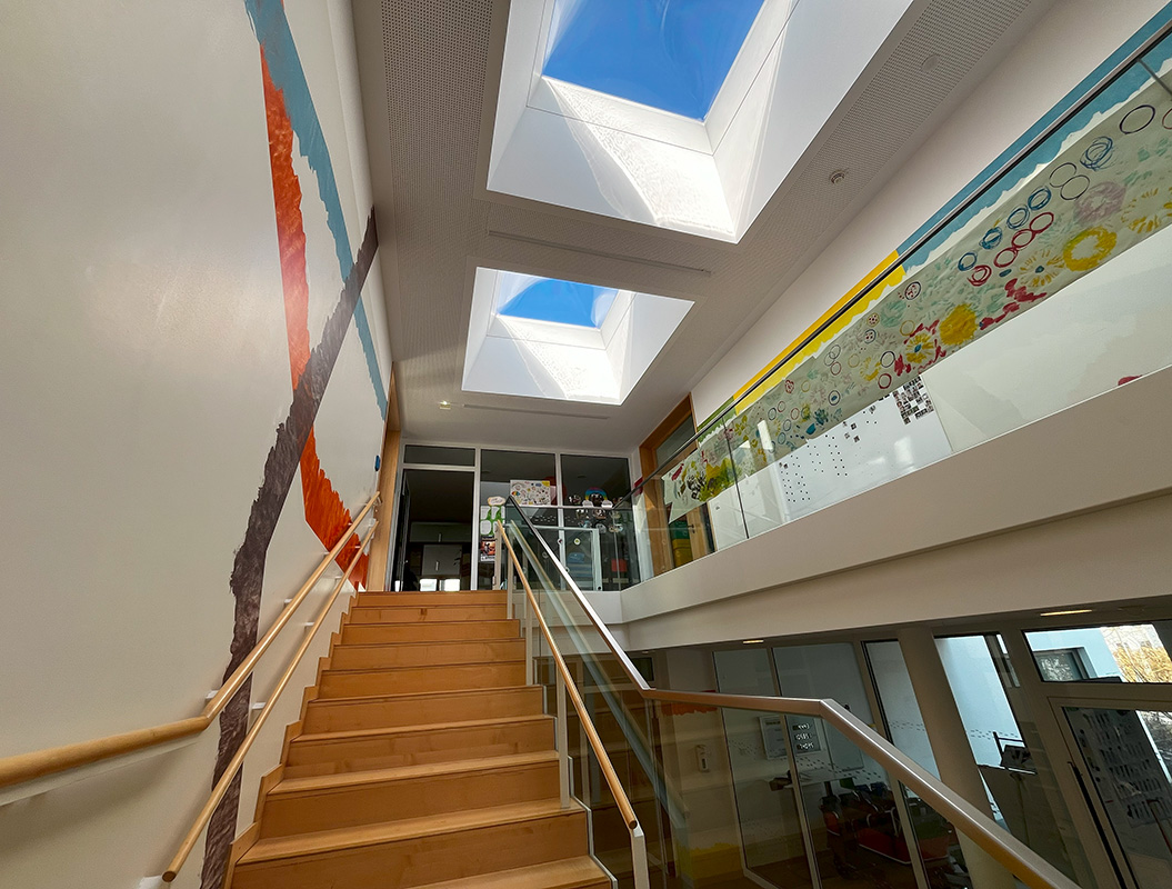 Eine modern gestaltete Treppe mit bunten Wandmalereien und Glasdachfenstern.