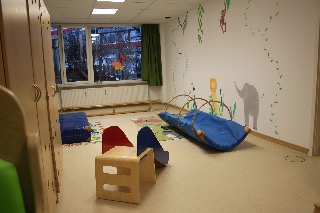 Ein leerer Kindergartenraum mit bunten Spielgeräten und Wandbemalungen.