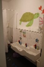 Ein Kinderbadezimmer, fröhlich dekoriert mit einer grünen Schildkröte an weißer Wand.