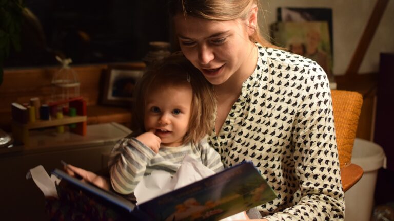 Mutter liest ihrer Tochter abends aus einem Buch vor.